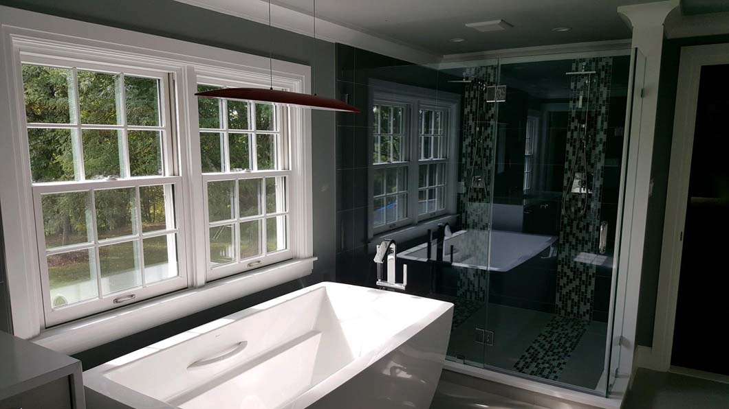 Free-standing bathtub in front of window in bathroom bathroom designed by Weinstein Allentown Bath & Kitchen Design Services